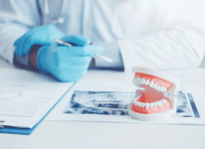 A dentist reviews documents beside a dental mold and X-ray image at a dental practice.