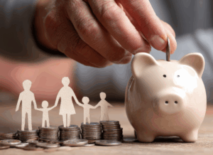Hand placing coin in piggy bank with paper cutout family standing on stacked coins, symbolizing the tax-deferred savings and Trump Accounts.