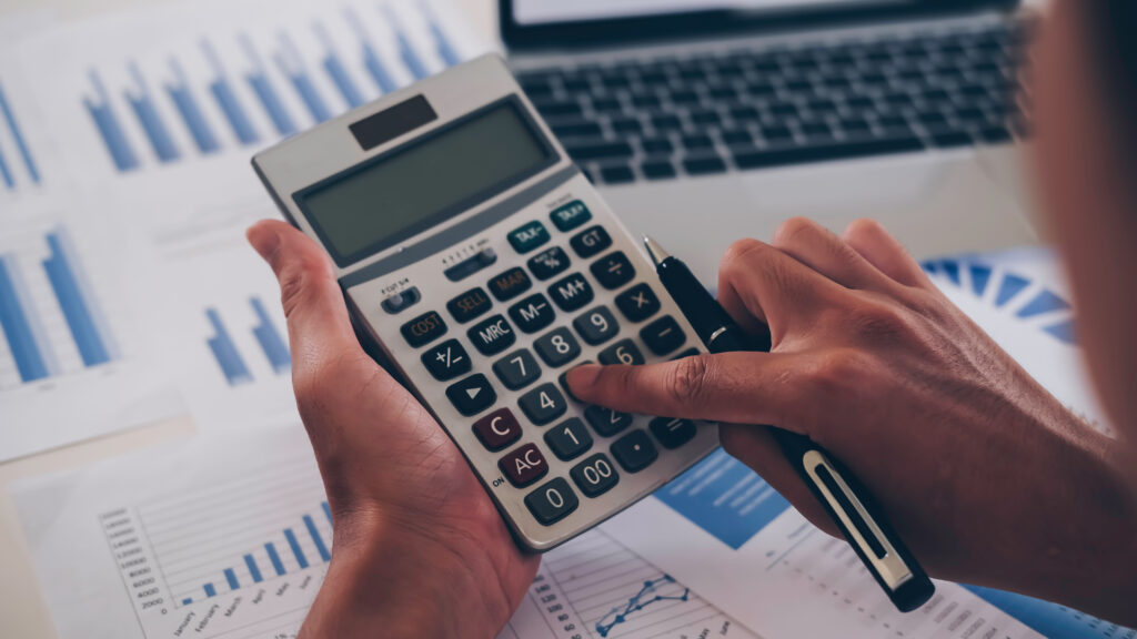 businessman or accountant working pointing graph discussion and analysis data charts and graphs and using a calculator to calculate numbers. Business finances and accounting concept