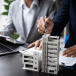 Business professionals review documents with commercial building models on a desk, symbolizing commercial rent sales tax.