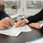 Two professionals review tax forms at a desk with a calculator, representing OBBBA and bonus depreciation planning.