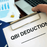 A clipboard labeled QBI Deduction with financial charts in the background, symbolizing the QBI deduction under the OBBBA.