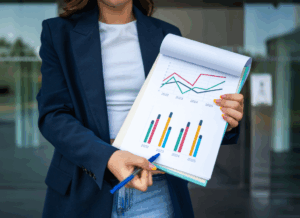 A woman holds a report with colorful charts and graphs, illustrating growth trends, representing financial forecasting for nonprofits.