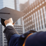A graduate holds up a cap against a city skyline, symbolizing progress and innovation driven by AI adoption in higher education.