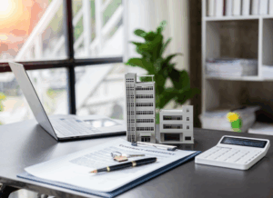 Office desk with building models, calculator, and contract documents, illustrating accounting for hotel renovations and capital improvement planning.