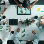 A team reviews green energy charts and solar models at a table, illustrating planning efforts related to the advanced manufacturing tax credit.