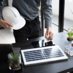 A developer reviews plans with solar panels and wind models on a desk, representing changes in green energy tax credits for businesses.