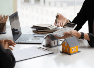 Areal estate CPA reviews numbers beside model houses and a laptop, illustrating guidance on choosing the right structure for real estate family office planning.
