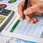 A person reviews financial documents with a calculator and a balance sheet summary, illustrating how to prepare a construction company balance sheet.