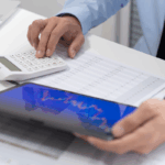 An investor reviews data on a tablet and calculator, representing analysis and planning for qualified small business stock investments.