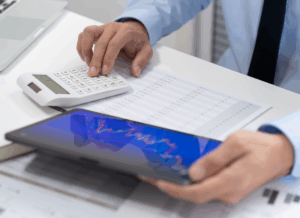 An investor reviews data on a tablet and calculator, representing analysis and planning for qualified small business stock investments.