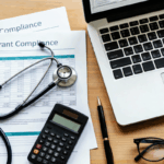 Healthcare documents labeled “Grant Compliance” sit on a desk with a stethoscope, calculator, and laptop, representing Grant Compliance & Tracking for FQHCs.