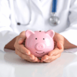 A doctor holds a pink piggy bank in both hands, symbolizing savings and financial security through Physician Retirement Planning.