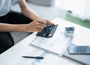 Person using a calculator to review financial documents and property models related to the estate and gift tax exemption under the OBBBA.