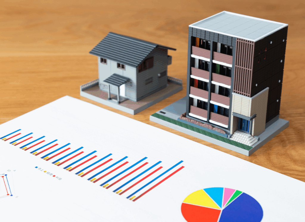 Property models beside financial charts illustrate analysis and planning for real estate risk management.