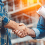 Two construction professionals shake hands at a job site, representing agreements and trust associated with types of contract bonds.