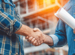 Two construction professionals shake hands at a job site, representing agreements and trust associated with types of contract bonds.
