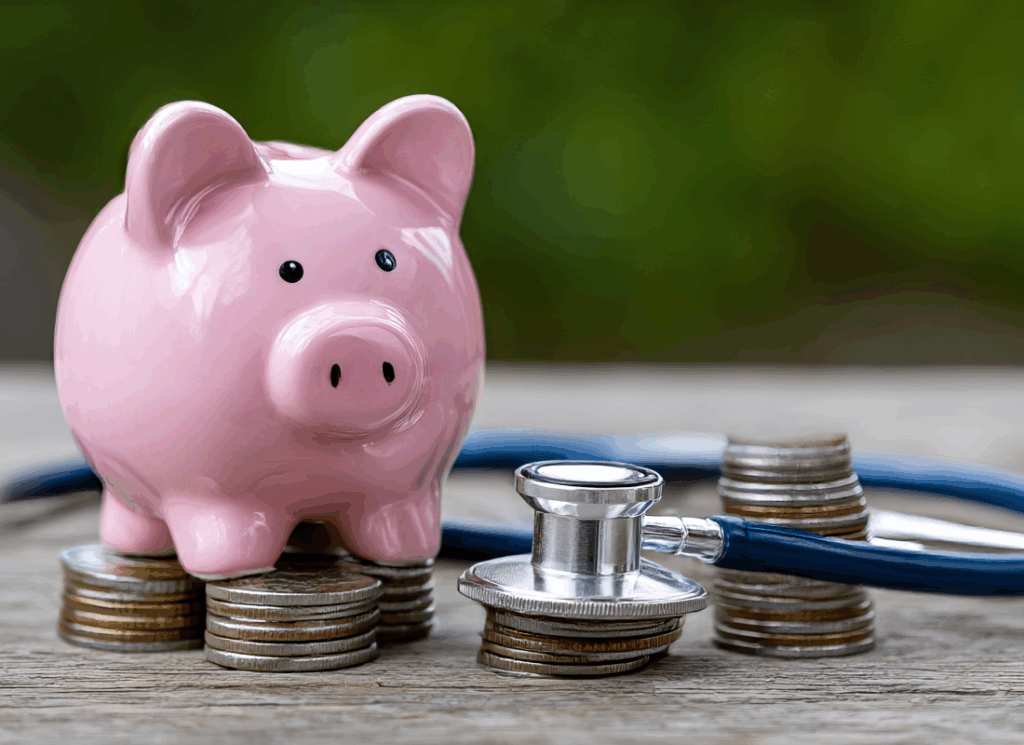 A pink piggy bank and stethoscope rest on stacks of coins, symbolizing financial planning and wealth management for physicians.