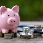 A pink piggy bank and stethoscope rest on stacks of coins, symbolizing financial planning and wealth management for physicians.