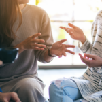 three people casually talking over coffee - focus on hands and coffee cup