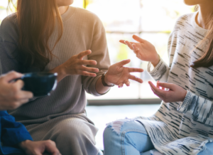 three people casually talking over coffee - focus on hands and coffee cup
