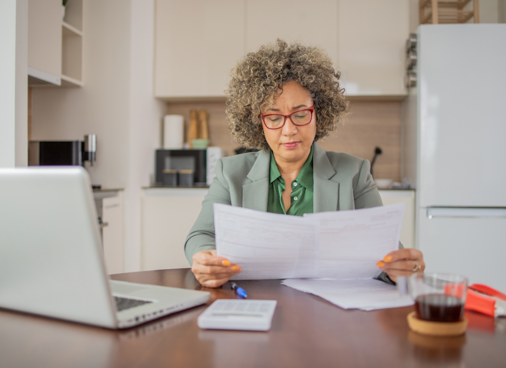 Woman at kitchen table, with computer, preparing her taxes.