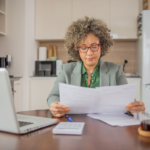 Woman at kitchen table, with computer, preparing her taxes.