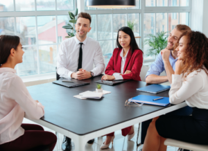 Hiring team interviewing a candidate at a conference table in a bright office setting.