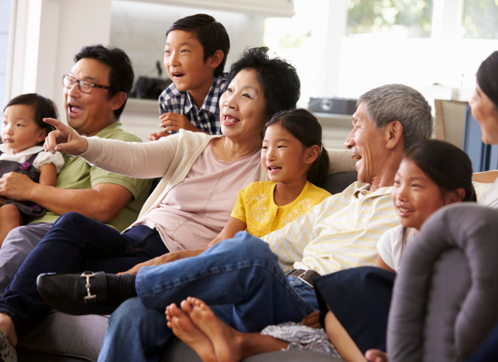 extended Asian family watching TV together and laughing