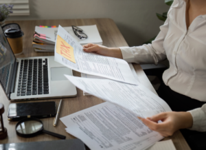 Person reviewing tax documents at a desk with a laptop and paperwork, analyzing forms for advanced retirement planning strategies.