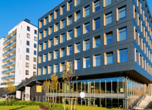 Modern multi-story commercial building with large windows and contemporary architectural design in an urban development area.