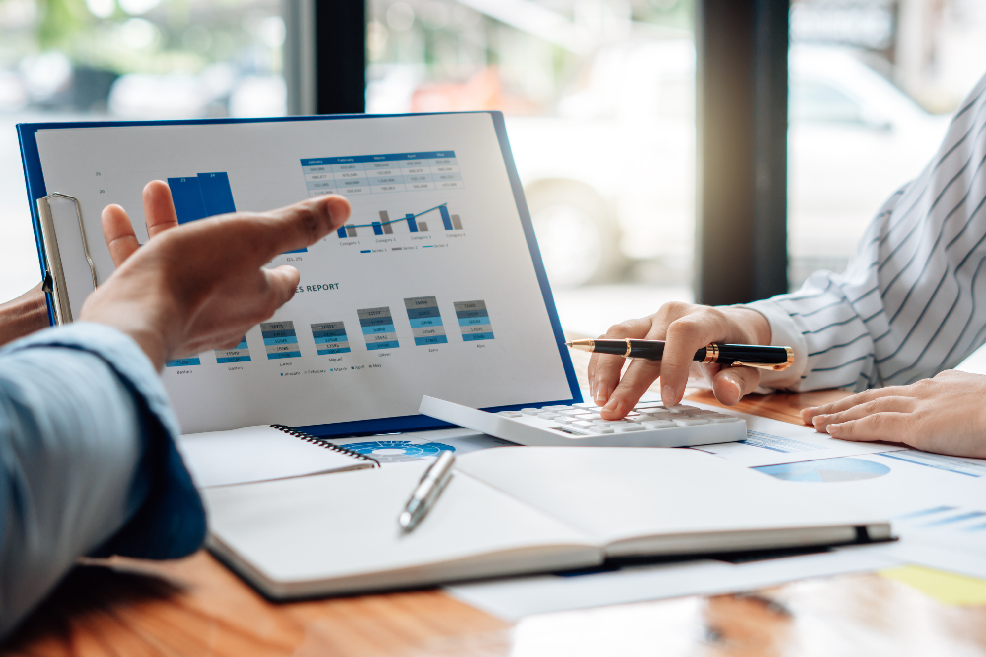 laptop with accounting software displayed and two people discussing