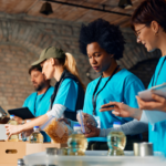 Volunteers at a nonprofit wearing matching shirts sort and pack food donations, including canned goods and pantry items, at a community distribution site.