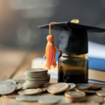 Graduation cap resting on a jar with stacked coins and books, symbolizing education funding and financial support.