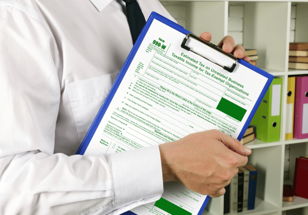 Audited Financial Statements featured image 1100 x 800 (77) A person in business attire is holding a clipboard with a form 990.