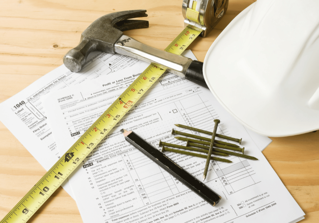 A hardhat and construction tools sitting on top of tax forms.