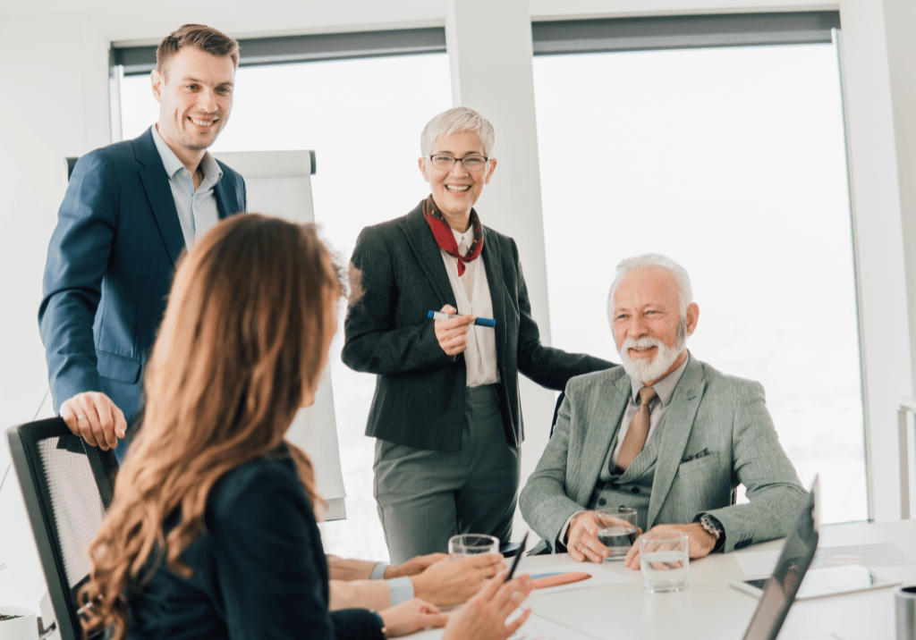 People of different ages are at a table in a business office setting.