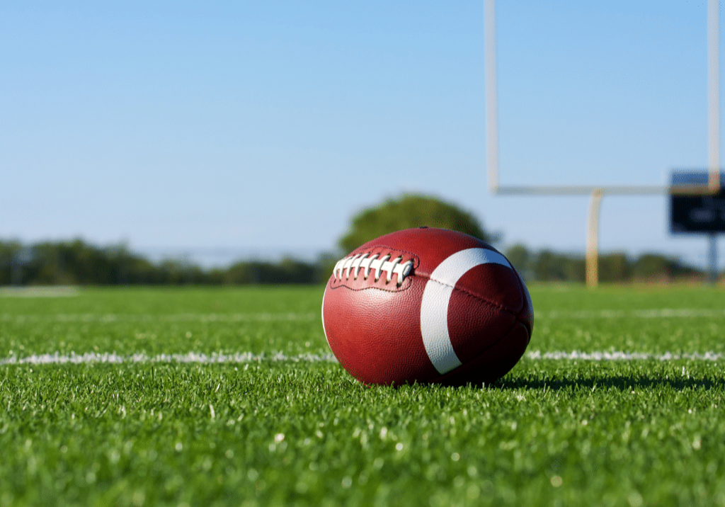 NCAA reporting featured image 1100 x 800 (81) A football is shown close up on football field. The goalposts our visible in the background.