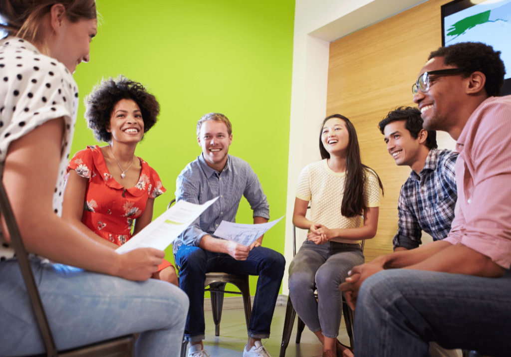 NP CPE Series blog post featured image 1100 x 800 (19) A group of six people are sitting on chairs in a circle and smiling.