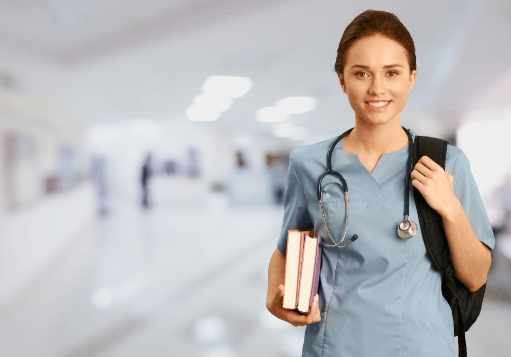 A nurse is carrying a bag and books. She has a stethoscope and is wearing nurses scrubs.