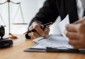 Understanding Government FS featured image A business person is reviewing documents on a clipboard, while holding a pen and sitting at a wooden desk.