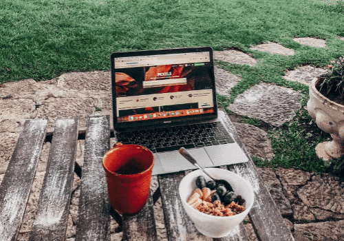 breakfast of healthy cereal and coffee in front of laptop, symbolizing employee wellness measures