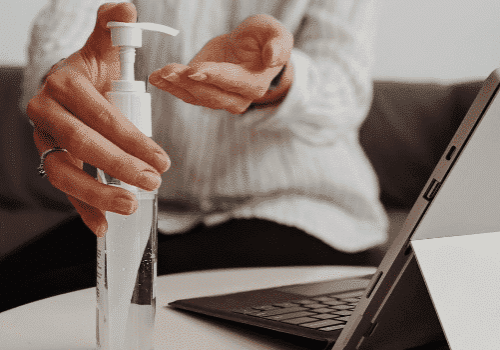 official c19 workplace guidance 550x350 closeup of employee using hand sanitizer by computer in compliance with COVID-19 workplace guidance